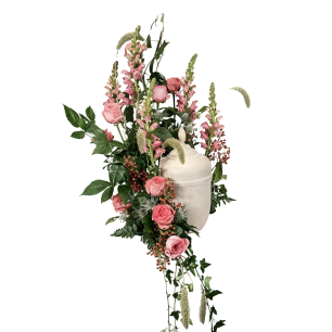 Beige urna omgiven av rosa rosor och gröna blad.